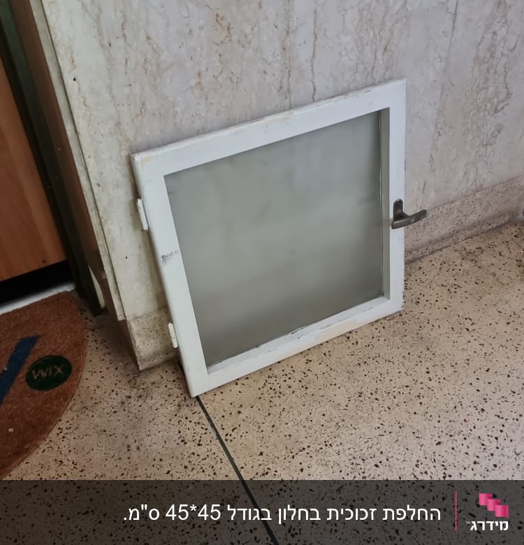 חלון זכוכית עם מסגרת לבנה על הרצפה